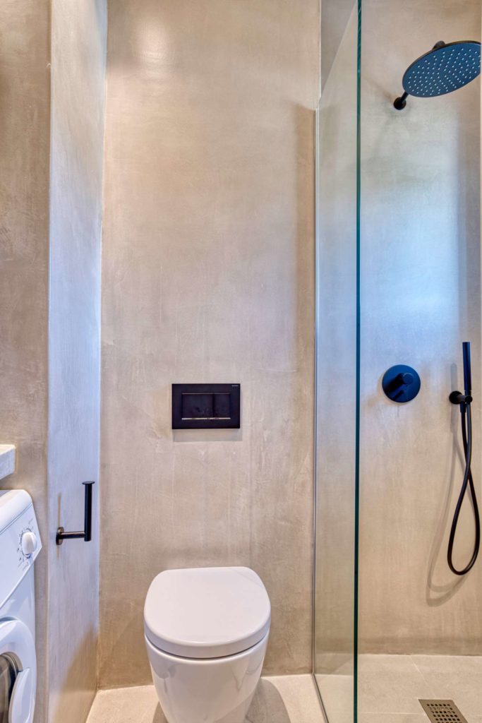 The walk-in shower behind glass, with a black rainfall shower head