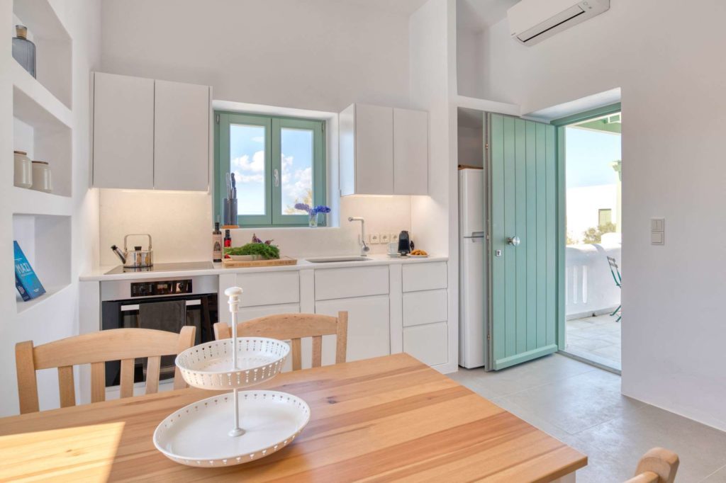 The dining table with the mint-green terrace door open beyond it