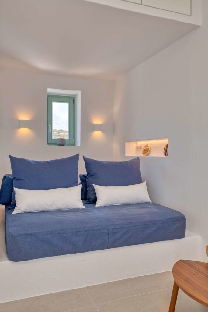 The blue sofa bed made up with cushions under two wall lights