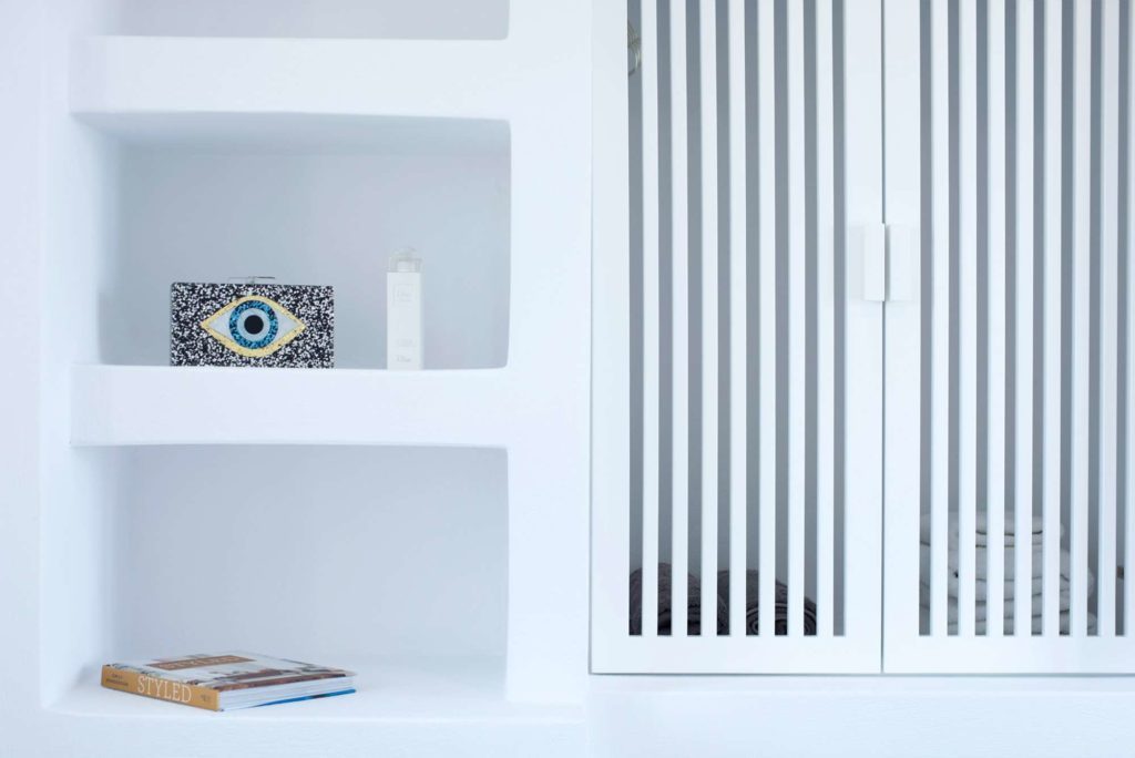 Built-in white shelving with books and a folk-art evil eye ornament