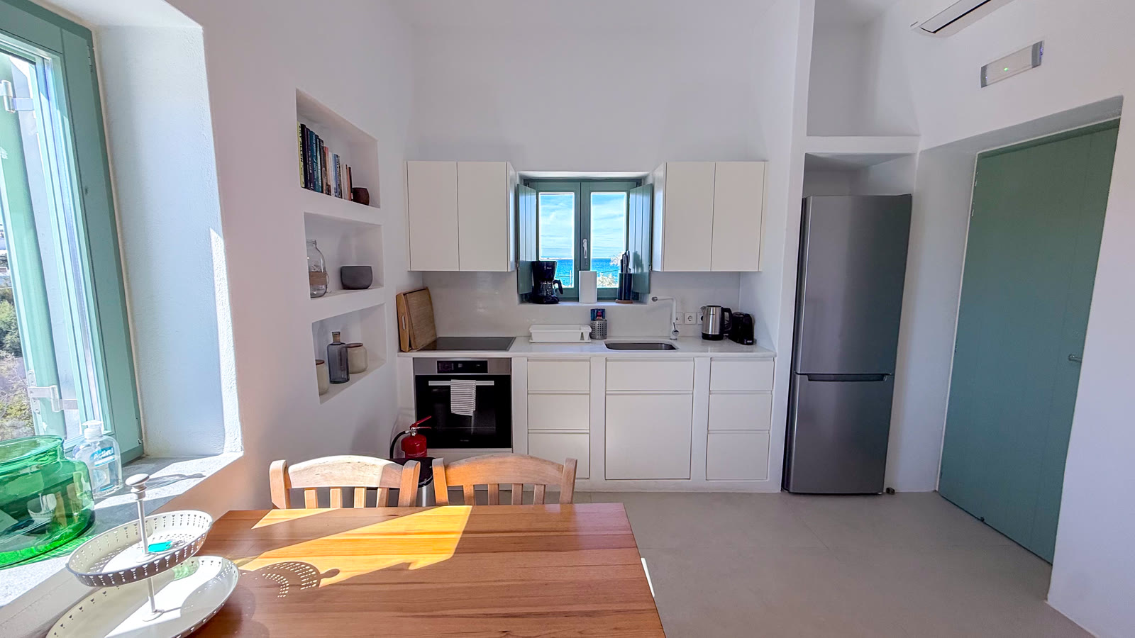 The refreshed white kitchen and sunlit wooden dining table for four