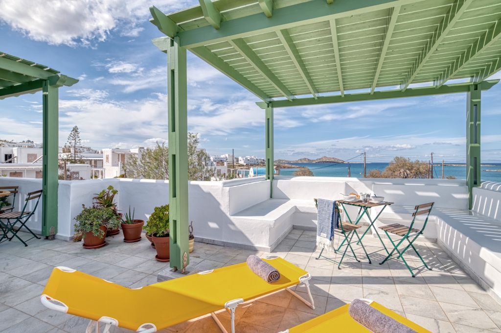 The terrace laid out for the day: sun loungers, potted plants and the bay beyond the wall