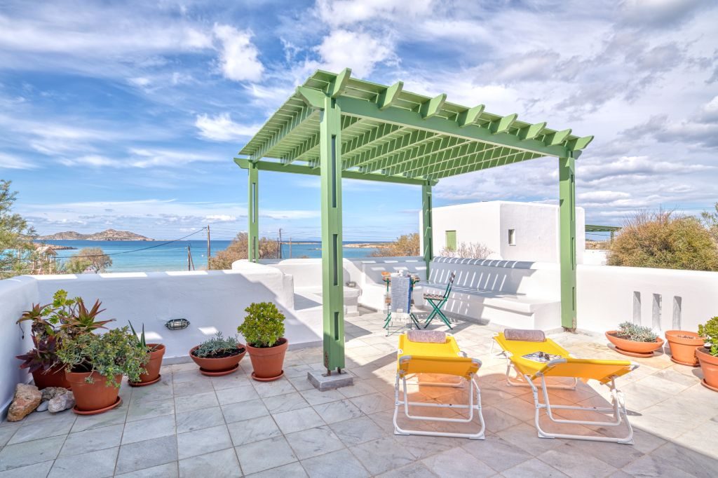 The terrace at May Lola with the pergola, sun loungers and the bay beyond