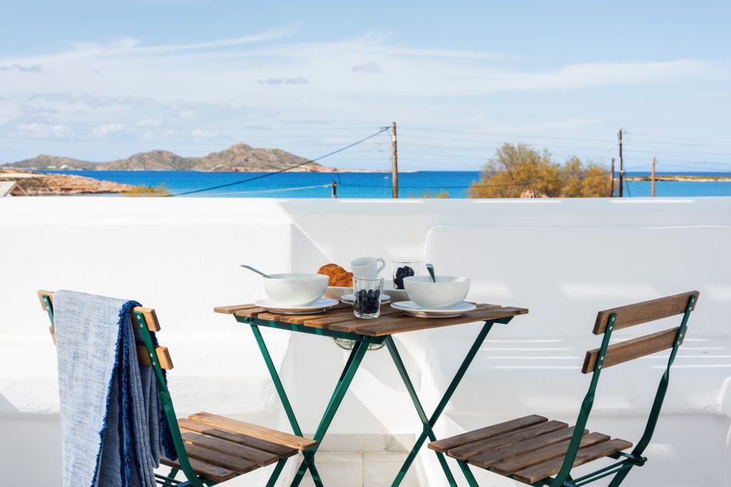 Breakfast laid on the terrace table with a towel over the chair and the sea beyond